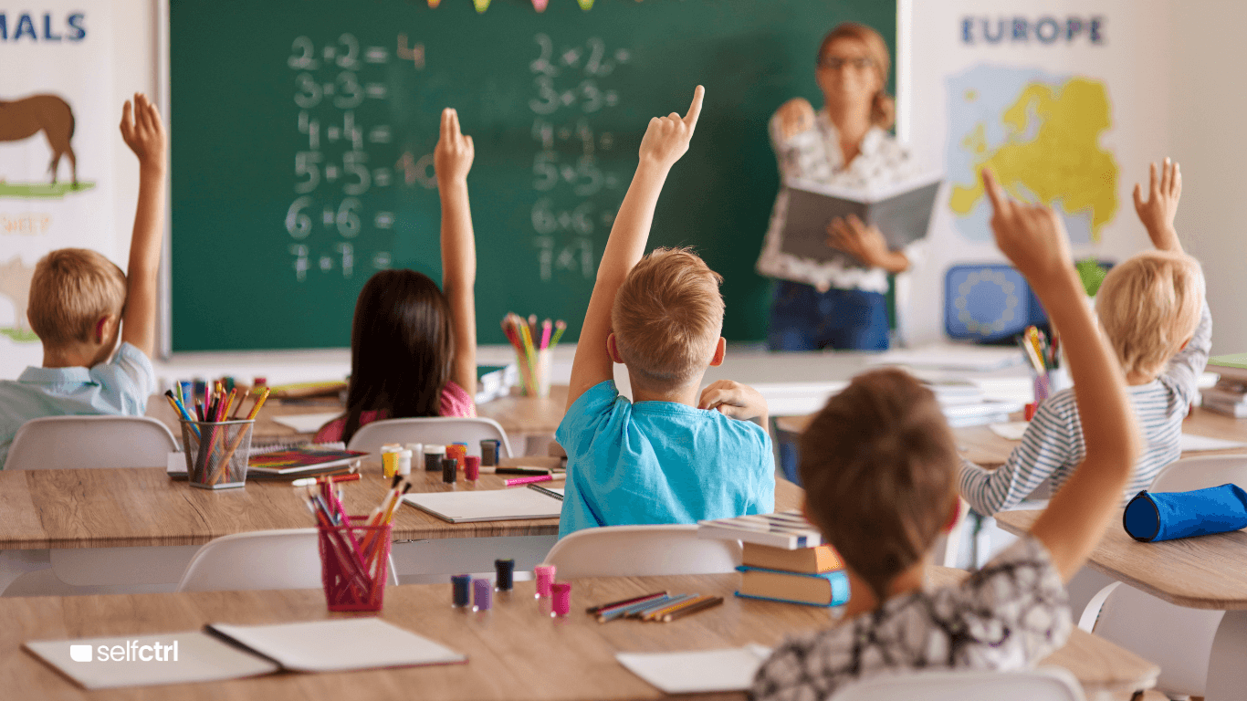 Teacher in a classroom with kids hands raised no screen in sight