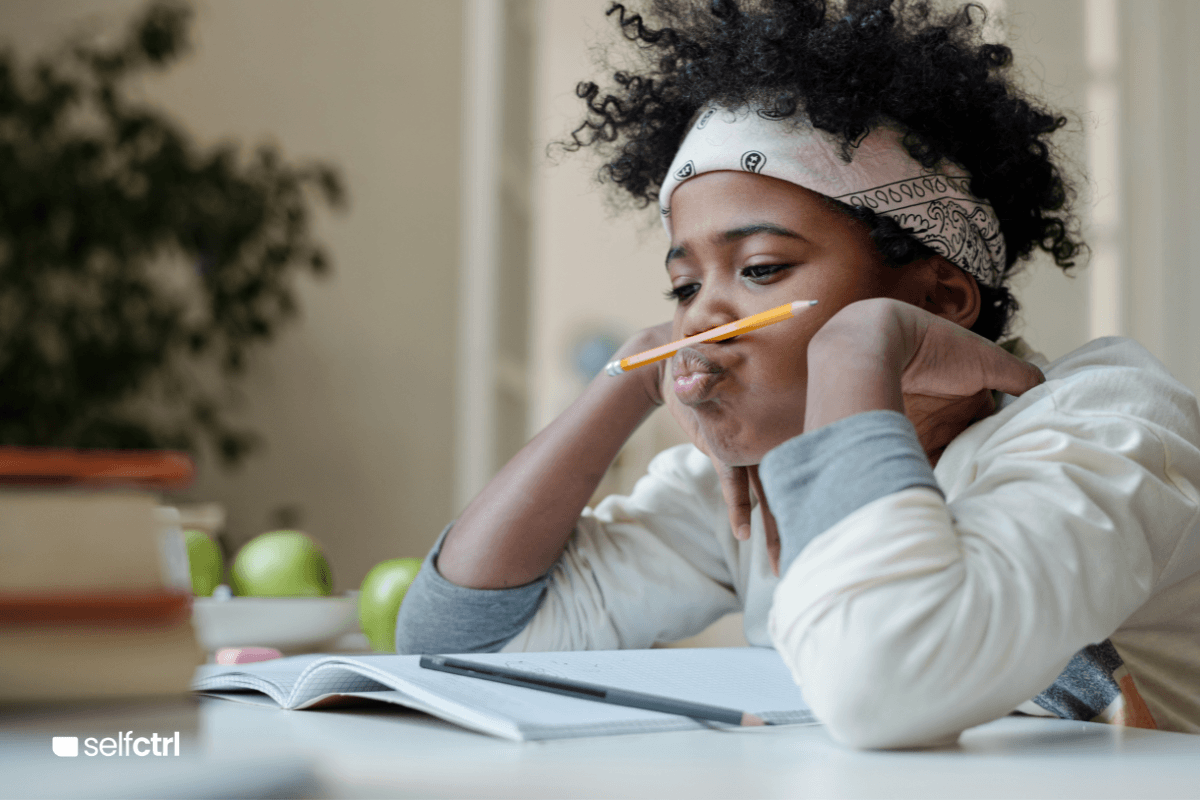 Little girl with a headband and her cute curls spilling over while she balances a pencil between her nose and lips as her little kid attention span struggles to stay focused