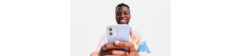 Black man smiling while scrolling and typing on his phone during vacation