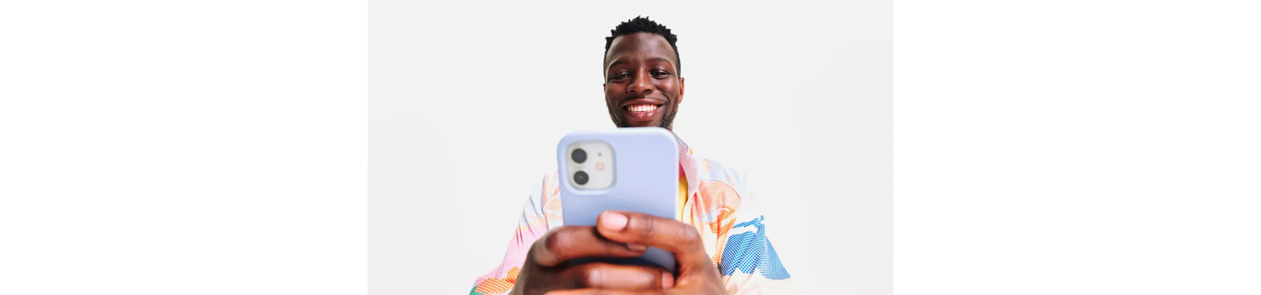 Black man smiling while scrolling and typing on his phone during vacation