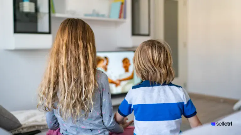 2 Kids watching a tv screen together in the morning